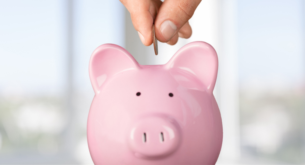 Man putting a coin into a piggy bank