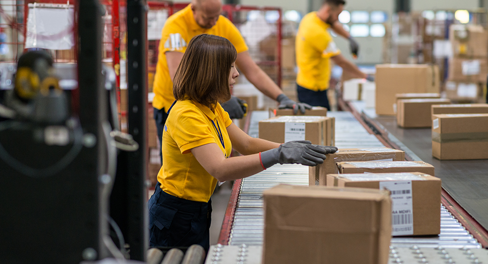 Staff lifting and moving boxes off assembly line