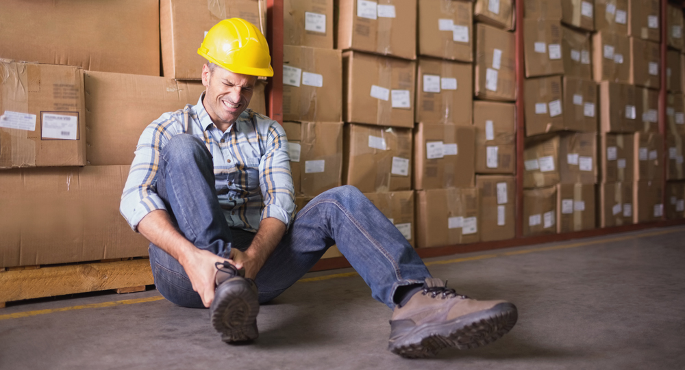 Injured employee holding ankle while sitting on ground