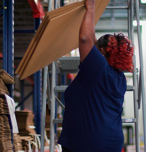 Employee using ladder to pull down boxes 